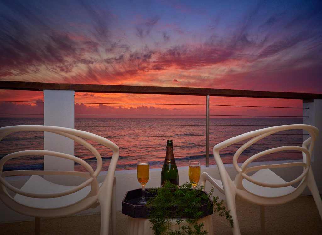 Atardecer naranja y violeta desde la terraza, con dos copas